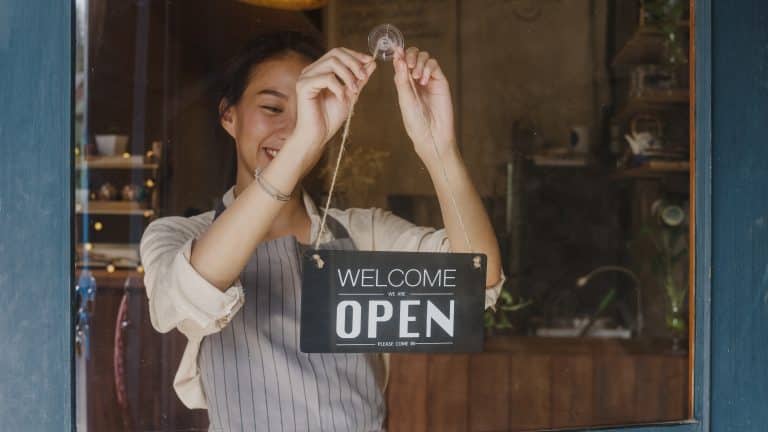 Young Asia manager girl changing a sign from closed to open sign